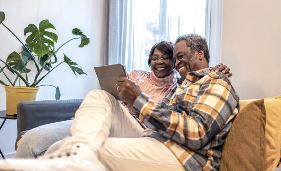 couple sitting in room looking at tablet